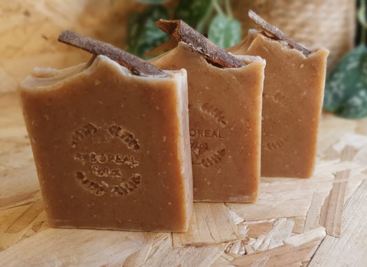 Three bars of soap with a brand logo on a wooden surface